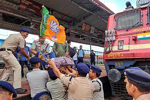 BJP's Bengal Bandh: Police personnel detain a BJP worker as party activists block trains at Kharagpur railway station in West Medinipur